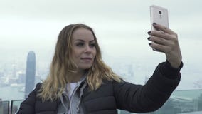 Счастливая девушка перемещения принимая мобильную панораму города Гонконга selfie Туристская женщина фотографируя портрет selfie видеоматериал Счастливая девушка перемещения принимая мобильную панораму города Гонконга selfie Туристская женщина фотографируя портрет selfie видеоматериал