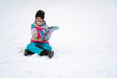 Счастливая девушка сидя на снеге в зиме Ребенок в костюме лыжи с ее руками показывает на космосе экземпляра стоковое изображение Счастливая девушка сидя на снеге в зиме Ребенок в костюме лыжи с ее руками показывает на космосе экземпляра стоковое изображение