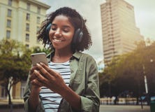 Счастливая девушка слушая музыку просматривая умное содержание телефона стоковые изображения Счастливая девушка слушая музыку просматривая умное содержание телефона стоковые изображения