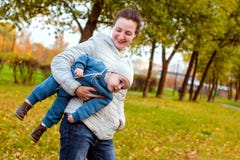 Счастливая любящая семья в парке Мать в белизне и ребенок в сини имея потеху, играя и смеясь в природе стоковое изображение Счастливая любящая семья в парке Мать в белизне и ребенок в сини имея потеху, играя и смеясь в природе стоковое изображение