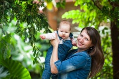 Счастливая молодая женщина держа младенца вне на прогулке в парке стоковые изображения Счастливая молодая женщина держа младенца вне на прогулке в парке стоковые изображения