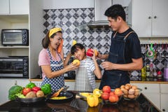 Счастливая семья имеет папы, мамы и их маленькой дочери варя совместно в кухне стоковая фотография rf Счастливая семья имеет папы, мамы и их маленькой дочери варя совместно в кухне стоковая фотография rf
