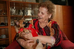 Счастливая, усмехаясь бабушка с подарком рождества, щенок чихуахуа с красной лентой стоковое фото Счастливая, усмехаясь бабушка с подарком рождества, щенок чихуахуа с красной лентой стоковое фото