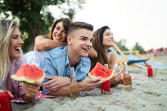 Счастливые друзья имея потеху на пляже и есть арбуз стоковая фотография rf Счастливые друзья имея потеху на пляже и есть арбуз стоковая фотография rf
