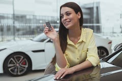 Счастливые ключи автомобиля удерживания женщины к ее новому автомобилю стоковые фото Счастливые ключи автомобиля удерживания женщины к ее новому автомобилю стоковые фото
