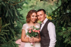 Счастливые молодые пары, белокурая невеста в светлом белом изумительном платье свадьбы, держащ букет розовых цветков, и выхолить стоковая фотография Счастливые молодые пары, белокурая невеста в светлом белом изумительном платье свадьбы, держащ букет розовых цветков, и выхолить стоковая фотография