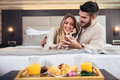 Счастливые пары имея завтрак в комнате роскошного отеля стоковые фотографии rf Счастливые пары имея завтрак в комнате роскошного отеля стоковые фотографии rf