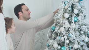 Счастливые родители и их сын украшая рождественскую елку в живущей комнате стоковое изображение Счастливые родители и их сын украшая рождественскую елку в живущей комнате стоковое изображение