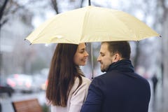 Счастливые романтичные пары, парень и его девушка одетые в случайных одеждах идут под зонтик и взгляд на одине другого стоковые изображения Счастливые романтичные пары, парень и его девушка одетые в случайных одеждах идут под зонтик и взгляд на одине другого стоковые изображения