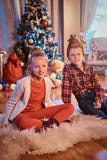 Счастливый брат и сестра сидя на ковре меха около рождественской елки дома стоковые фото Счастливый брат и сестра сидя на ковре меха около рождественской елки дома стоковые фото