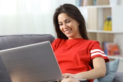 Счастливый девочка-подросток используя ноутбук на кресле дома стоковые изображения rf Счастливый девочка-подросток используя ноутбук на кресле дома стоковые изображения rf