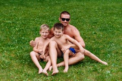 Счастливый молодой отец обнимает 2 жизнерадостных сыновей летом на зеленой лужайке Человек и усмехаясь дети стоковое изображение Счастливый молодой отец обнимает 2 жизнерадостных сыновей летом на зеленой лужайке Человек и усмехаясь дети стоковое изображение