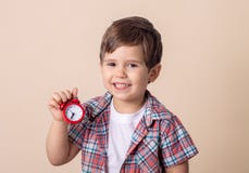 Счастливый ребенок держа красные часы на серой предпосылке E стоковая фотография Счастливый ребенок держа красные часы на серой предпосылке E стоковая фотография