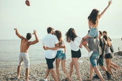 Счастливый укомплектовывает личным составом и прогулка женщины на группе в составе пляжа друзья наслаждаясь праздниками пляжа стоковое изображение rf Счастливый укомплектовывает личным составом и прогулка женщины на группе в составе пляжа друзья наслаждаясь праздниками пляжа стоковое изображение rf