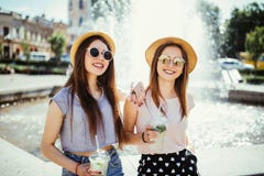 2 счастливых красивых девушки имея потеху выпивают mojito в солнечном летнем дне идя в улицу около фонтана Образ жизни, перемещен стоковые фотографии rf 2 счастливых красивых девушки имея потеху выпивают mojito в солнечном летнем дне идя в улицу около фонтана Образ жизни, перемещен стоковые фотографии rf
