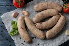 Сырцовые сосиски с ингредиентами для варить томаты, чеснок, масло и базилик на голубом деревянном столе над взглядом стоковое фото rf Сырцовые сосиски с ингредиентами для варить томаты, чеснок, масло и базилик на голубом деревянном столе над взглядом стоковое фото rf