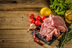Сырцовые стейки свинины на каменной доске с травами, томатами, чесноком и стоковые фото Сырцовые стейки свинины на каменной доске с травами, томатами, чесноком и стоковые фото