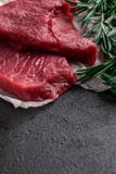 Сырцовый стейк говядины со свежим розмариновым маслом ветвей на черной предпосылке стоковое фото rf Сырцовый стейк говядины со свежим розмариновым маслом ветвей на черной предпосылке стоковое фото rf