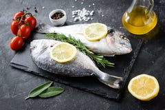 Сырые рыбы, оливковое масло, лимон и специи леща моря на шифере стоковые фотографии rf Сырые рыбы, оливковое масло, лимон и специи леща моря на шифере стоковые фотографии rf