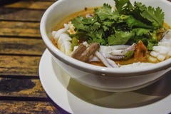 Тайская кухня - гарнир супа кальмара пряный с кориандром в белом шаре на деревянном столе, очень вкусном обедающем стоковая фотография rf Тайская кухня - гарнир супа кальмара пряный с кориандром в белом шаре на деревянном столе, очень вкусном обедающем стоковая фотография rf