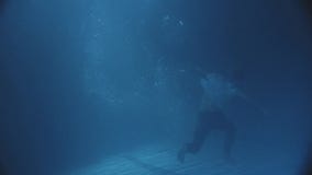 Танцующ человек под водой в темном бассейне, с некоторыми светами, он нося одевает сток-видео Танцующ человек под водой в темном бассейне, с некоторыми светами, он нося одевает сток-видео