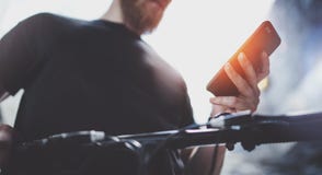 Татуированный мышечный мобильный телефон удерживания мужчины в руках и использовании приложения карты для подготовки маршрута дор стоковое фото Татуированный мышечный мобильный телефон удерживания мужчины в руках и использовании приложения карты для подготовки маршрута дор стоковое фото