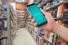 Телефон человеческим правым владением умный, таблетка, мобильный телефон с виртуальной e-библиотекой app на расплывчатых книжных Стоковые Изображения RF Телефон человеческим правым владением умный, таблетка, мобильный телефон с виртуальной e-библиотекой app на расплывчатых книжных Стоковые Изображения RF