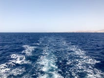 Текстура бурля голубой соленой воды моря с волнами, расслоины, пузыри, пена после стремительно плавая автомобиля, шлюпки против Стоковая Фотография RF Текстура бурля голубой соленой воды моря с волнами, расслоины, пузыри, пена после стремительно плавая автомобиля, шлюпки против Стоковая Фотография RF