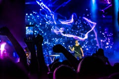 толпа согласия Силуэты людей на подсвеченном яркими голубыми и фиолетовыми светами этапа Веселя толпа в красочных светах этапа r стоковые изображения rf толпа согласия Силуэты людей на подсвеченном яркими голубыми и фиолетовыми светами этапа Веселя толпа в красочных светах этапа r стоковые изображения rf