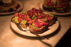 Тосты гуакамоле авокадоа с картошками вишни на плитах на счетчике кухни стоковое фото rf Тосты гуакамоле авокадоа с картошками вишни на плитах на счетчике кухни стоковое фото rf
