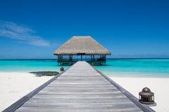 Тропический ландшафт пляжа с деревянным мостом и домом на воде на Maldive Тропический ландшафт пляжа с деревянным мостом и домом на воде на Maldive