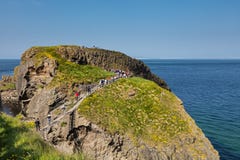 Туристы посещая мост веревочки Carrick-a-Rede в графстве антриме Северной Ирландии стоковые фотографии rf Туристы посещая мост веревочки Carrick-a-Rede в графстве антриме Северной Ирландии стоковые фотографии rf