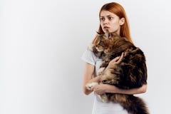 Удивленная женщина обнимая кота енота Мейна на светлой предпосылке стоковое фото rf Удивленная женщина обнимая кота енота Мейна на светлой предпосылке стоковое фото rf