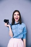 Удивленная молодая милая женщина держа камеру стоковые изображения rf Удивленная молодая милая женщина держа камеру стоковые изображения rf