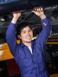 Уверенно механик работая под автомобилем Стоковая Фотография RF Уверенно механик работая под автомобилем Стоковая Фотография RF