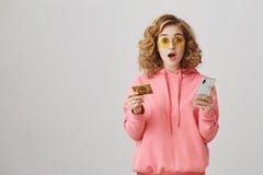 Удобная концепция банка и технологии Крытая съемка изумленной и довольной молодой женщины в ультрамодных стильных одеждах стоковое изображение Удобная концепция банка и технологии Крытая съемка изумленной и довольной молодой женщины в ультрамодных стильных одеждах стоковое изображение