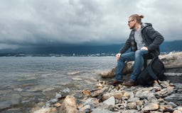 Укомплектуйте личным составом путешественника с seets рюкзака на seashore против предпосылки облаков и концепции горной цепи пеше Стоковое Изображение Укомплектуйте личным составом путешественника с seets рюкзака на seashore против предпосылки облаков и концепции горной цепи пеше Стоковое Изображение