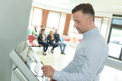 Укомплектуйте личным составом делать регистрацию на столе самопомощи в авиапорте Стоковые Изображения RF Укомплектуйте личным составом делать регистрацию на столе самопомощи в авиапорте Стоковые Изображения RF