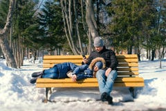 Укомплектуйте личным составом и остатки женщины совместно на стенде в парке города зимы стоковая фотография rf Укомплектуйте личным составом и остатки женщины совместно на стенде в парке города зимы стоковая фотография rf