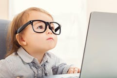 Умная девушка малыша нося большие стекла пока использующ ее компьтер-книжку Стоковая Фотография RF Умная девушка малыша нося большие стекла пока использующ ее компьтер-книжку Стоковая Фотография RF