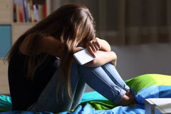 Унылое предназначенное для подростков с телефоном в ее спальне стоковое фото rf Унылое предназначенное для подростков с телефоном в ее спальне стоковое фото rf