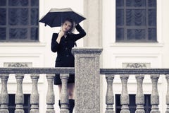 Унылая молодая женщина моды с зонтиком идя в улицу города Стоковые Фото Унылая молодая женщина моды с зонтиком идя в улицу города Стоковые Фото