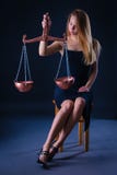 Усаженный на девушку стула очаровывая с Libra в ее руке как символ знака зодиака воздуха стоковые изображения Усаженный на девушку стула очаровывая с Libra в ее руке как символ знака зодиака воздуха стоковые изображения