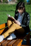 Усаживание и чтение маленькой девочки книга на солнечный и красивый весенний день в парке на стенде стоковые фотографии rf Усаживание и чтение маленькой девочки книга на солнечный и красивый весенний день в парке на стенде стоковые фотографии rf