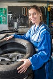 Усмехаясь женская автошина автомобиля установки механика на оправе в гараже Стоковые Фотографии RF Усмехаясь женская автошина автомобиля установки механика на оправе в гараже Стоковые Фотографии RF
