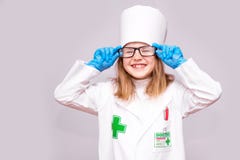 Усмехаясь маленькая девочка в медицинской форме и стеклах смотря изолированную камеру стоковые изображения Усмехаясь маленькая девочка в медицинской форме и стеклах смотря изолированную камеру стоковые изображения