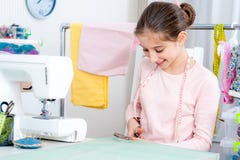 Усмехаясь маленькая девочка работая на швейной машине стоковое изображение rf Усмехаясь маленькая девочка работая на швейной машине стоковое изображение rf