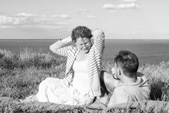 Усмехаясь молодые пары сидя на траве близко воды Укомплектуйте личным составом класть на траву смотря на женщине красных волос сч стоковое фото rf Усмехаясь молодые пары сидя на траве близко воды Укомплектуйте личным составом класть на траву смотря на женщине красных волос сч стоковое фото rf