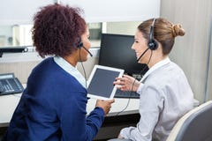 Усмехаясь работники центра телефонного обслуживания обсуждая пока Стоковые Изображения Усмехаясь работники центра телефонного обслуживания обсуждая пока Стоковые Изображения