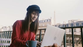 Усмехаясь счастливая элегантная коммерсантка используя ноутбук, смотря Эйфелеву башню на завтраке на идилличном балконе утра Пари акции видеоматериалы Усмехаясь счастливая элегантная коммерсантка используя ноутбук, смотря Эйфелеву башню на завтраке на идилличном балконе утра Пари акции видеоматериалы